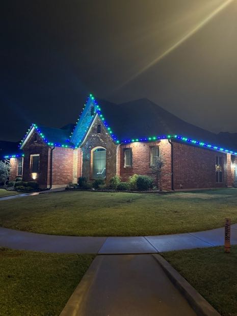 Brick home outlined in blue and white lights along the roofline and gables