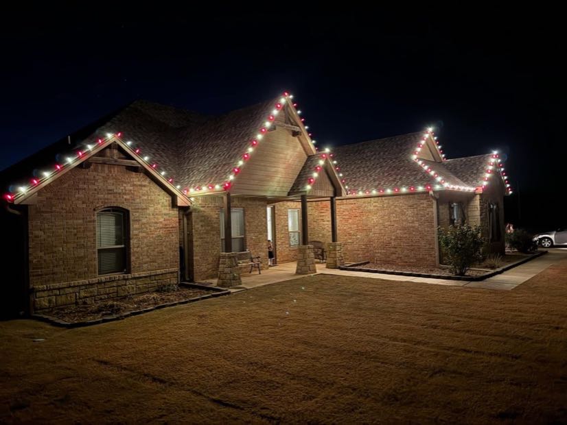 Brick home at night with crisp white C9 bulbs tracing the roofline and gable peaks