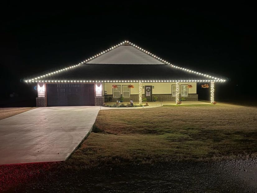Home with a wide covered porch outlined in warm white Christmas lights