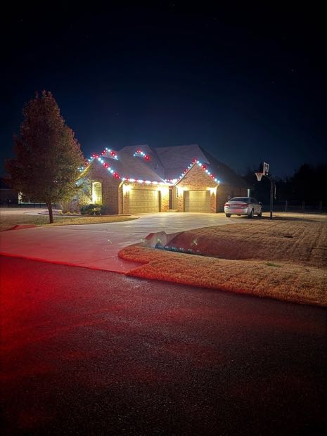Home lit in red and white with the driveway and lawn glowing red