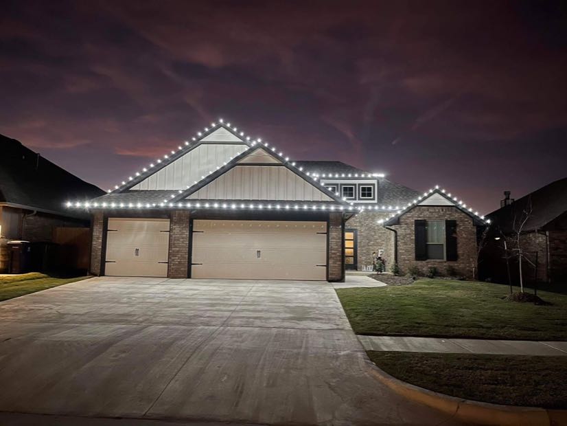 Two-car garage home with lights along the roofline and up the driveway