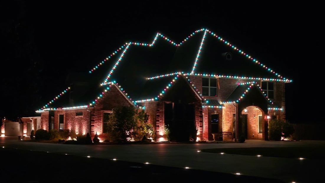 Large brick home with a multi-peaked roofline fully outlined in lights