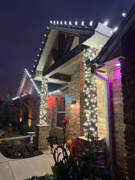 Home lit with white roofline lights and purple accent lighting on the brick