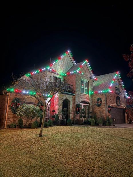 Two-story home outlined in red, green and white lights