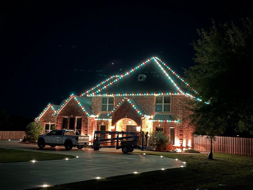 Home with warm white roofline lights and a lit pathway