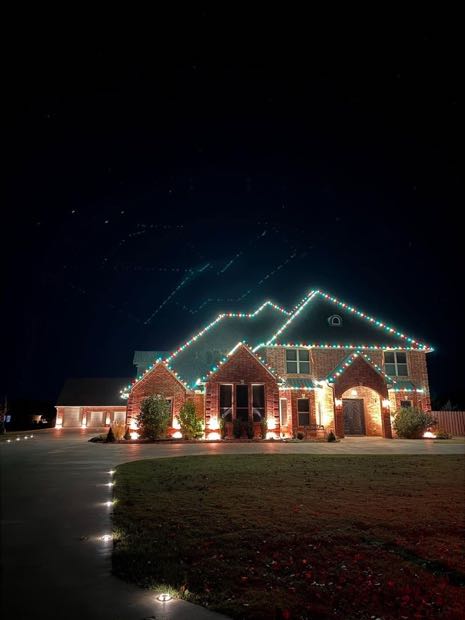 Brick home with white lights along every eave and gable