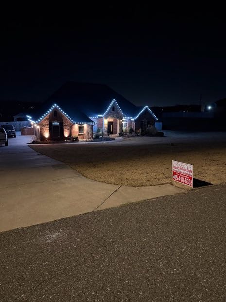 Home lit in warm white with a Haubrick yard sign in the lawn