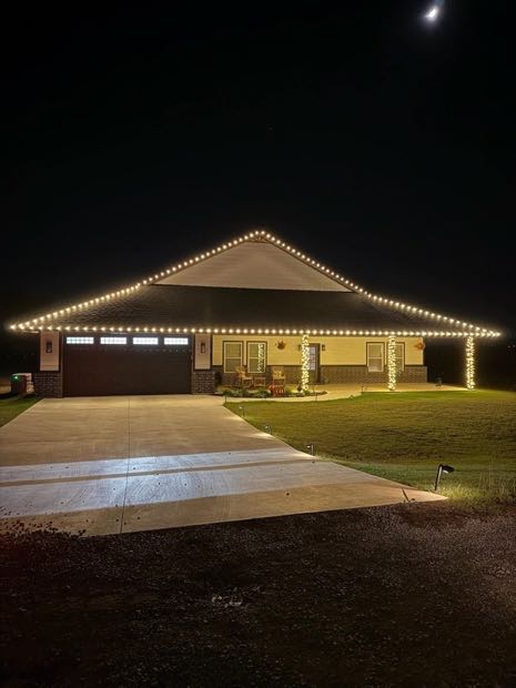 Single-story home with warm white lights along the roofline and garage