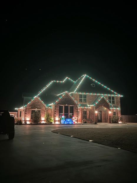 Stone and brick home outlined in bright white lights