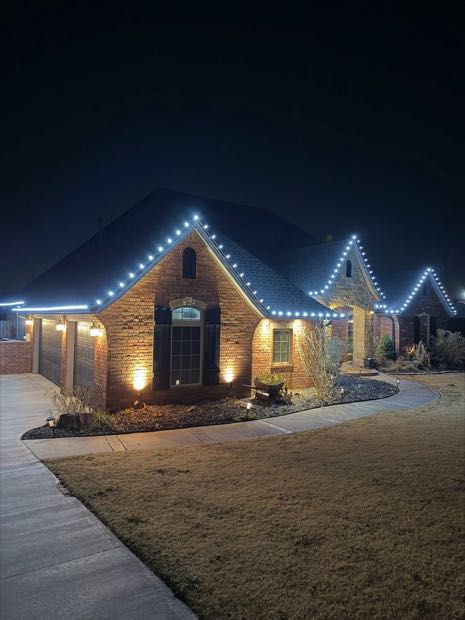 Brick home with white roofline lights and lit landscaping
