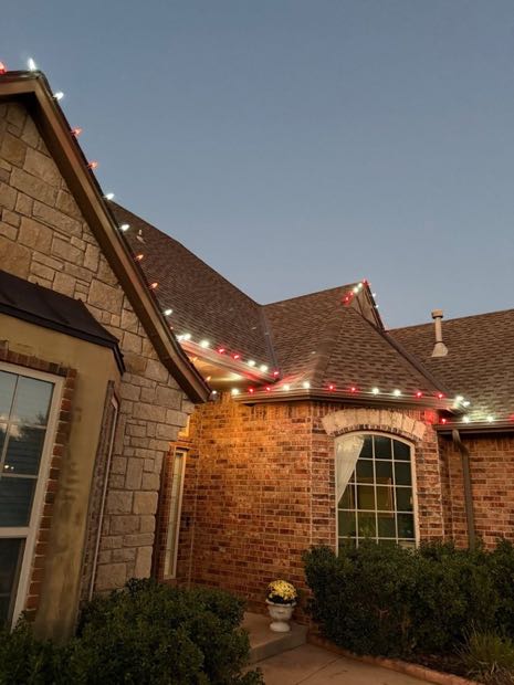 Home outlined in warm white lights with a lit front entry