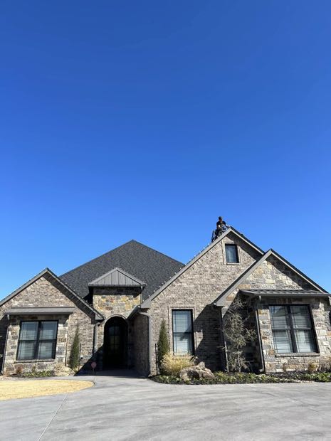 Stone home with fresh white roofline lights against a blue sky